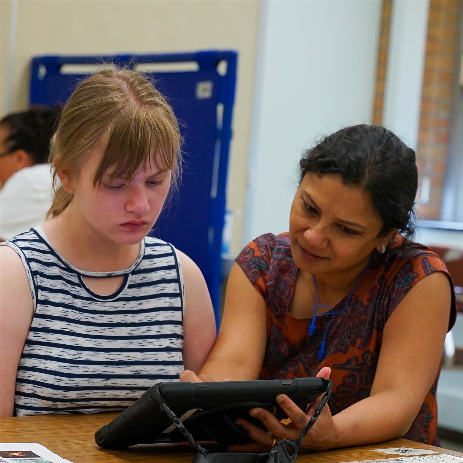 An instructor guides a student using a tablet.