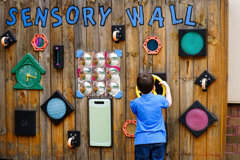 Child playing at outdoor sensory wall