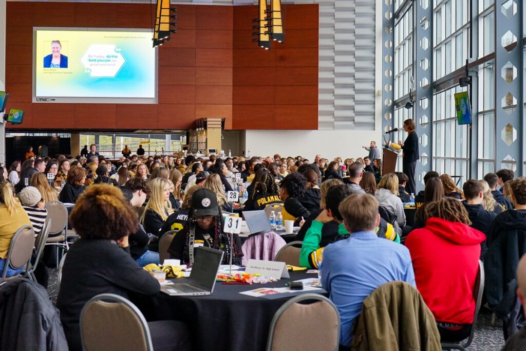 students listening to speaker in large conference space