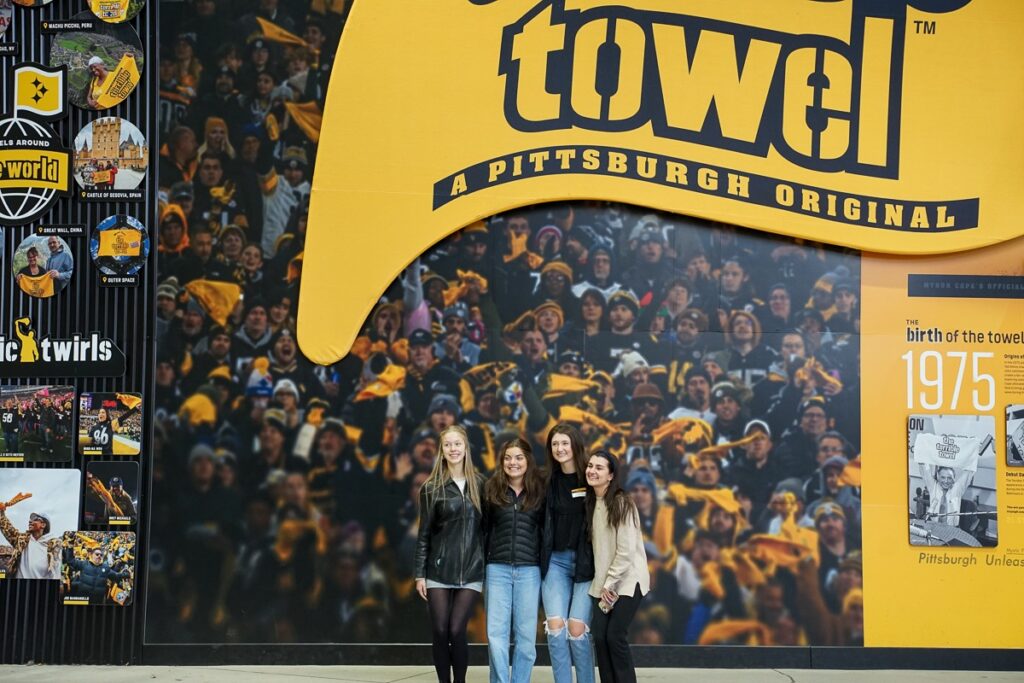 students posing in front of terrible towel during toor of stadium