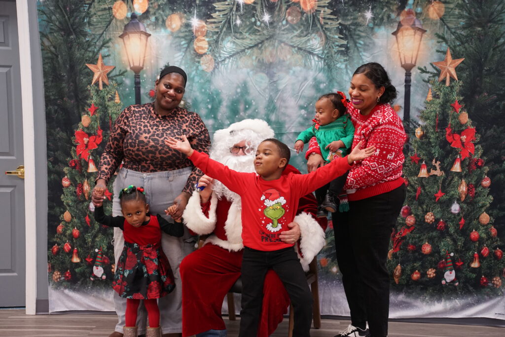 Photo of Santa Claus sitting in a chair surrounded by a family and three children