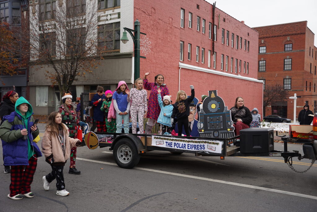 Photo of a truck trailer float in a christmas parade with children waving to the crowd