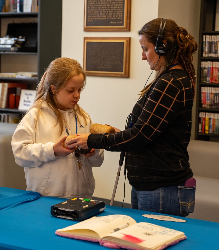 student and teacher interact with tactile display at library for accessible media