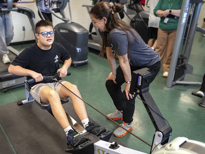 student uses exercise equipment with physical therapist