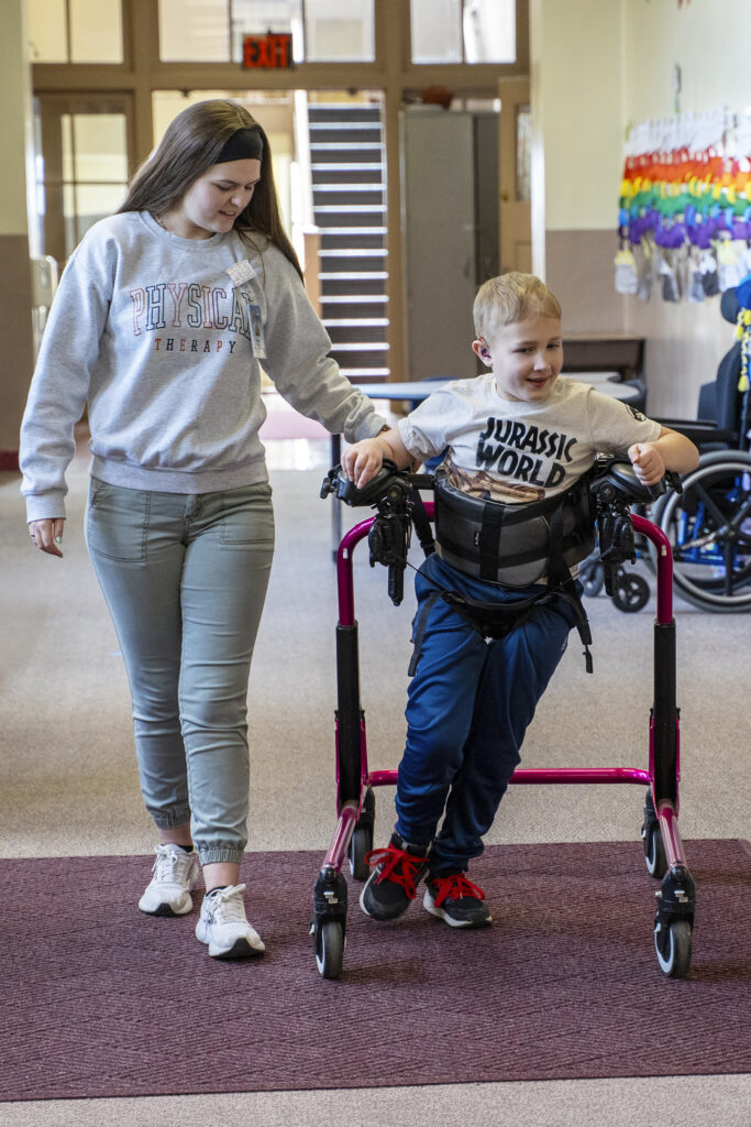 physical therapist helps student with mobility in school hallway
