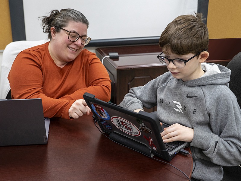 visually-impaired student works on laptop with teacher