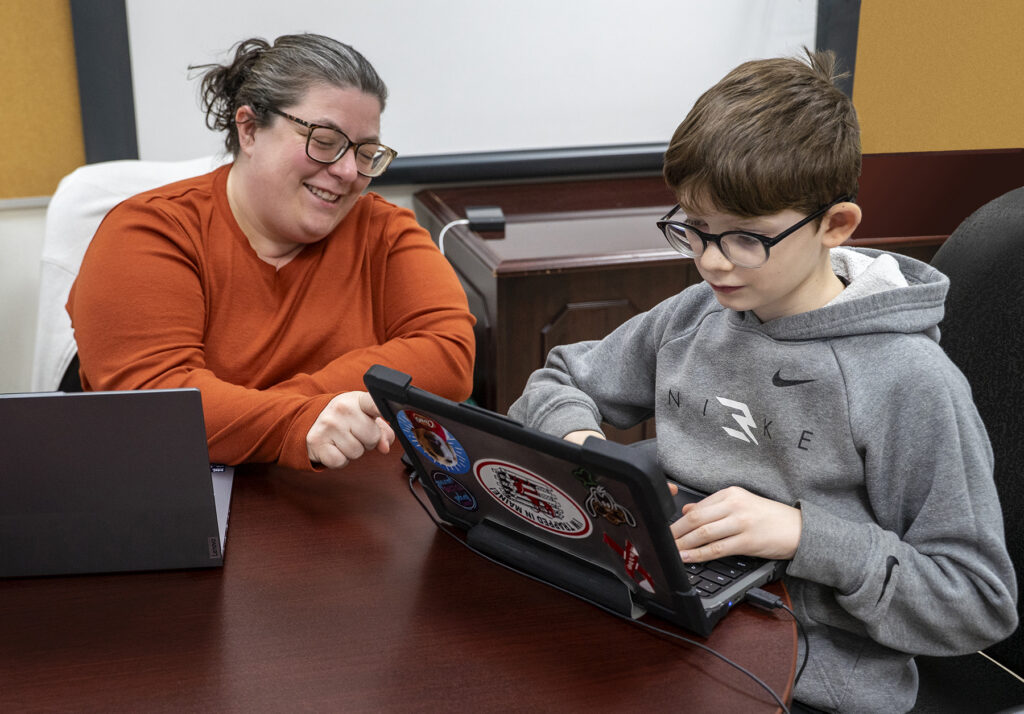 visually-impaired student works on laptop with teacher