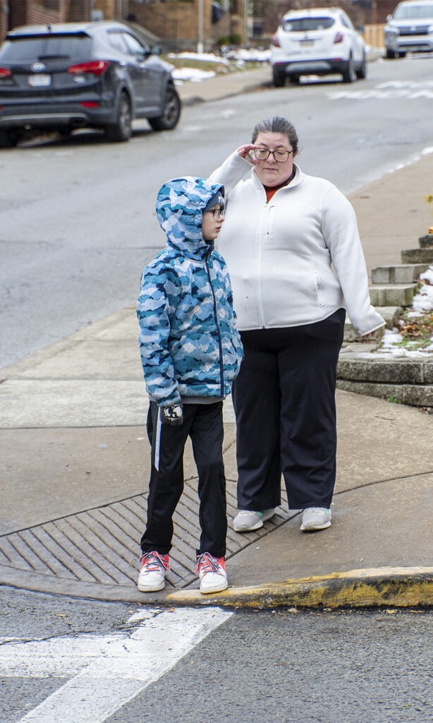 teacher helps visually-impaired student cross the street