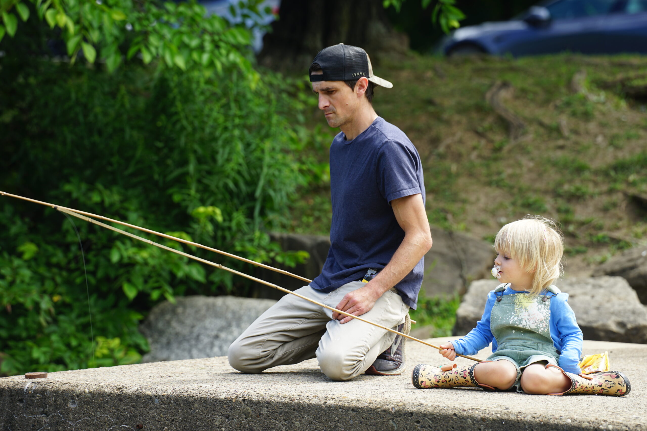 Father and daughter kneel fishing by the water