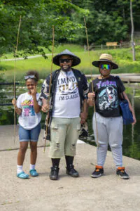Family poses with fishing rods by the lake