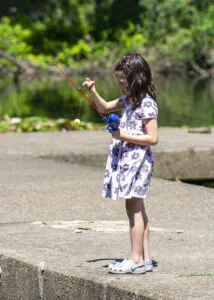a girl at the lake untangling a fishing line