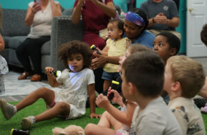 Children gathered around Ms. Robin as she tells a story