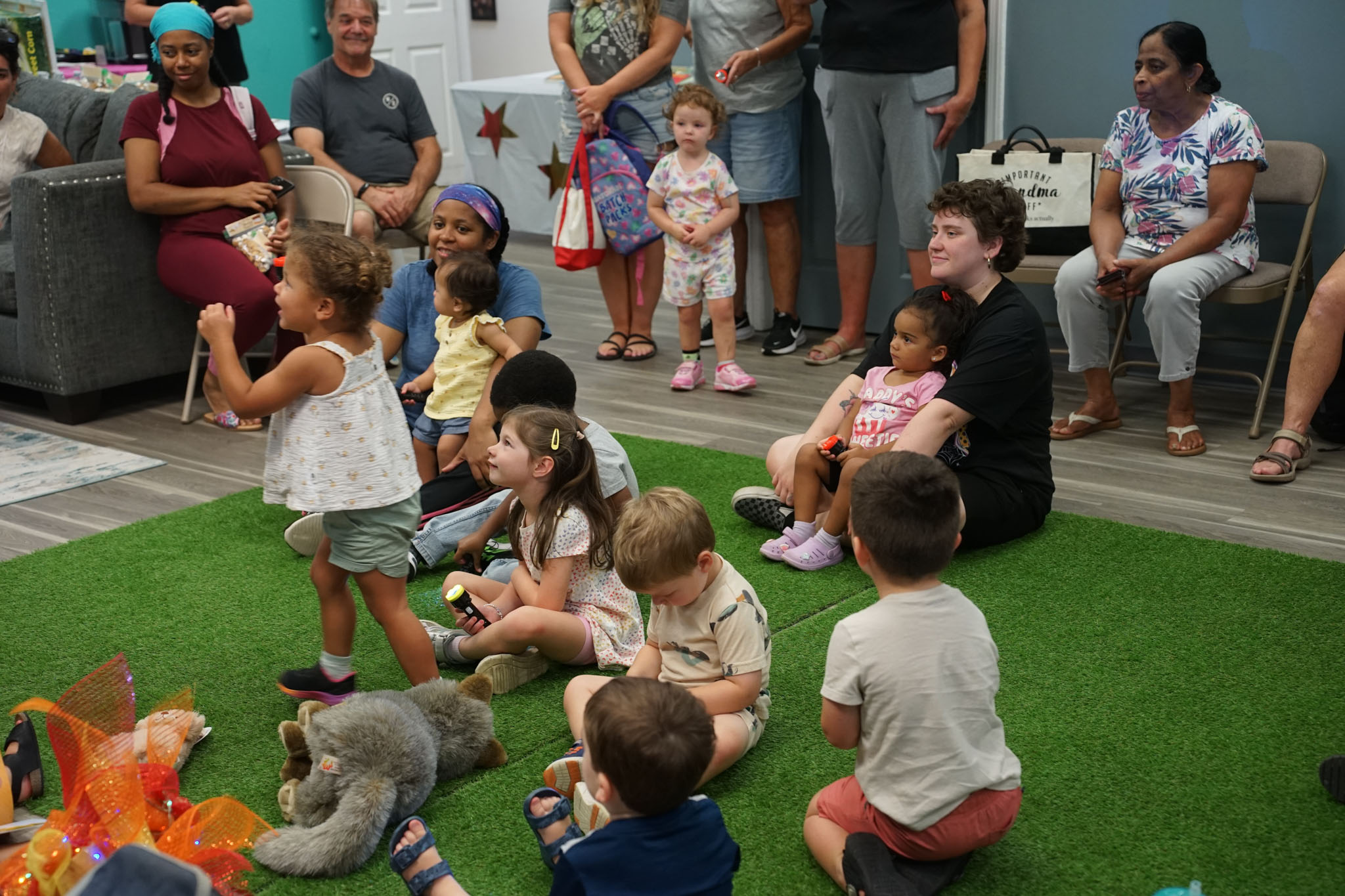 Children gathered around Ms. Robin as she tells a story