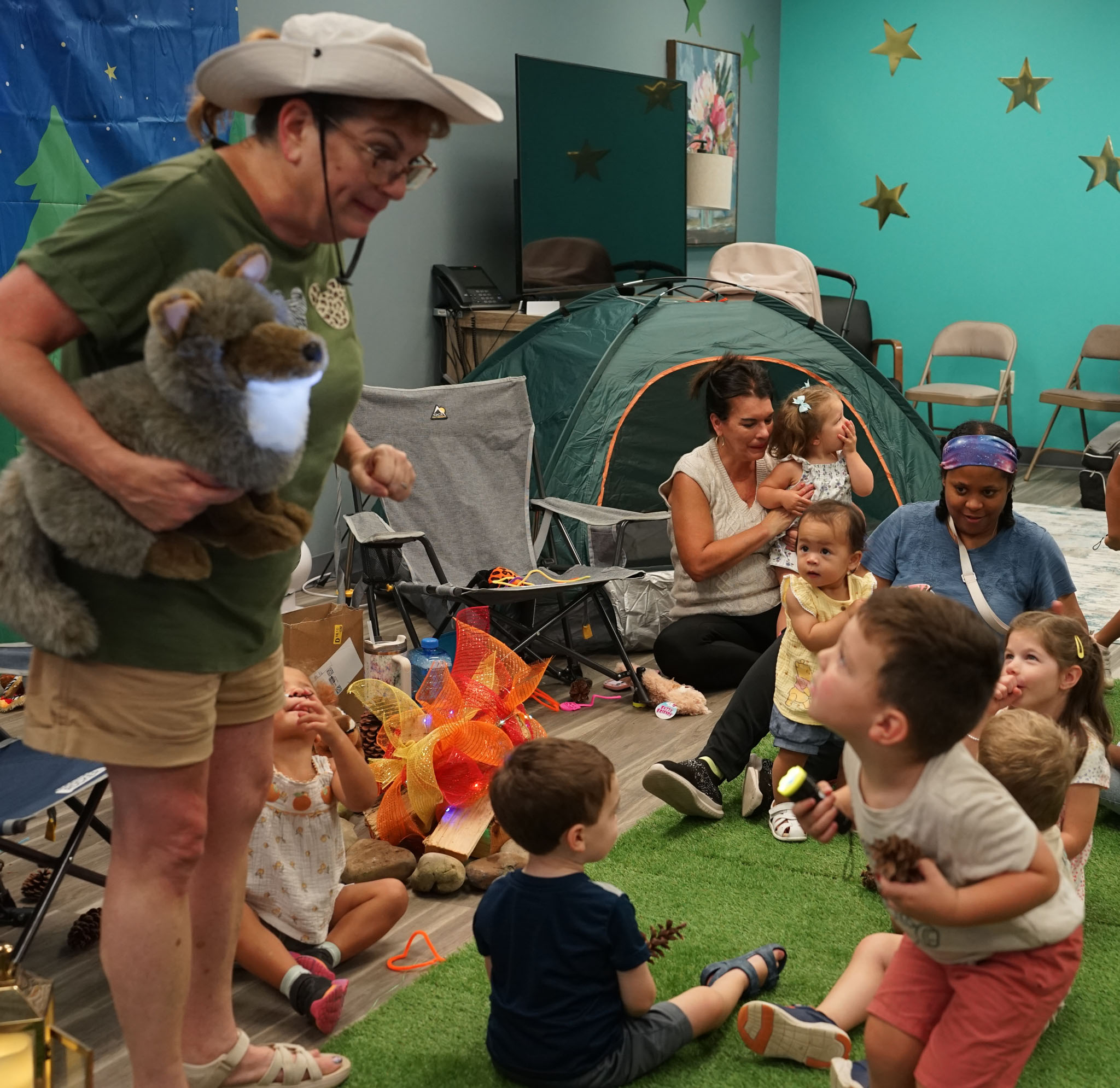 Children gathered around Ms. Robin as she tells a story