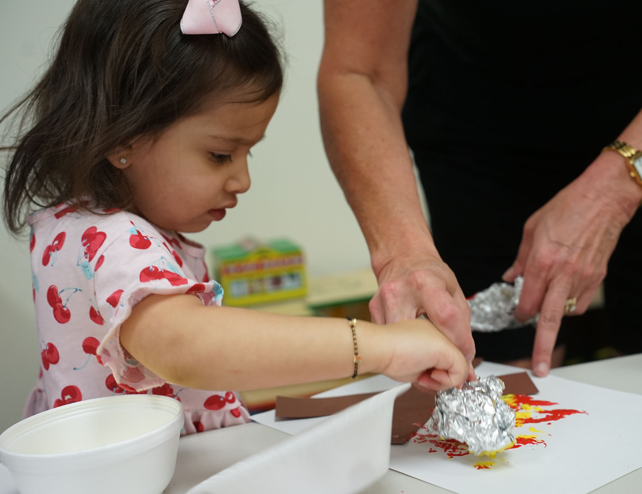 Child painting a campfire craft with tin foil and finger paint
