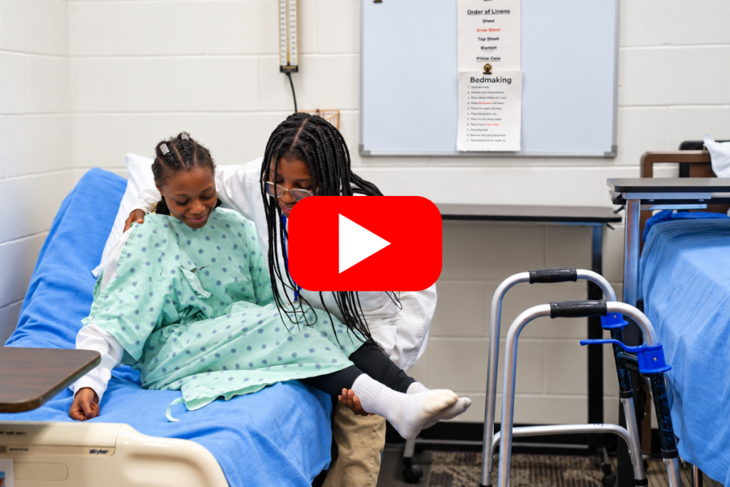 student helps another student into a hospital bed