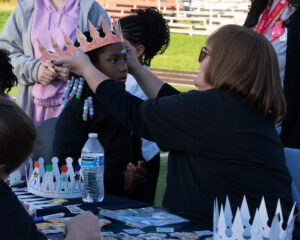 A vendor helps a young girl get fitted for a crown