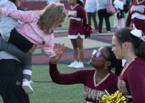 Cheerleaders give a high-five to a toddler