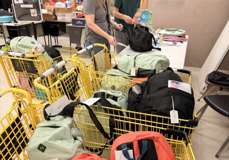 Student and teacher packing donations into school backpacks
